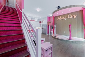 A staircase with a pink carpet leading to a reception area with a 'Music City' sign. - Barbie s Nashville Bachelorette Bash (Nashville)