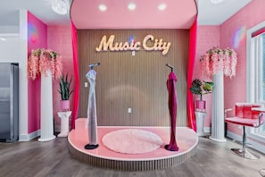 A salon with a pink and white color scheme, a 'Music City' sign, and a stage with a pink rug. - Barbie s Nashville Bachelorette Bash (Nashville)