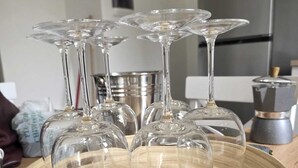Un plateau en bois sur lequel sont posés plusieurs verres à vin, sur un plan de travail de cuisine.