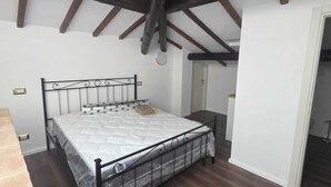 Une chambre à coucher avec un lit, des poutres en bois et un mur blanc.