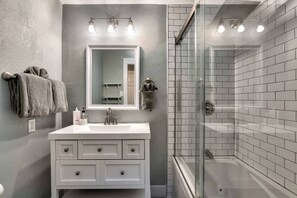 Un bagno con un mobile lavabo bianco, uno specchio grande e un box doccia in vetro.
