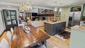 Une cuisine moderne dotée d’un îlot central, d’une table à manger en bois foncé et de meubles de rangement de couleur claire.