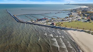An aerial view of a coastal area with a breakwater, marina, and residential buildings. - Walk to Beach & Pier | Fully-Loaded Kitchen (Sheboygan)