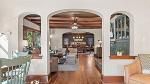 A spacious living area with a wooden ceiling, a central seating area, and a view into another room. - Walk to Beach & Pier | Fully-Loaded Kitchen (Sheboygan)