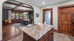 A spacious kitchen with a marble countertop, wooden cabinets, and a dining area with a chandelier. - Walk to Beach & Pier | Fully-Loaded Kitchen (Sheboygan)