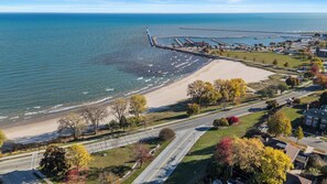 Vue aérienne d’une zone côtière avec une plage, une jetée et des immeubles résidentiels.