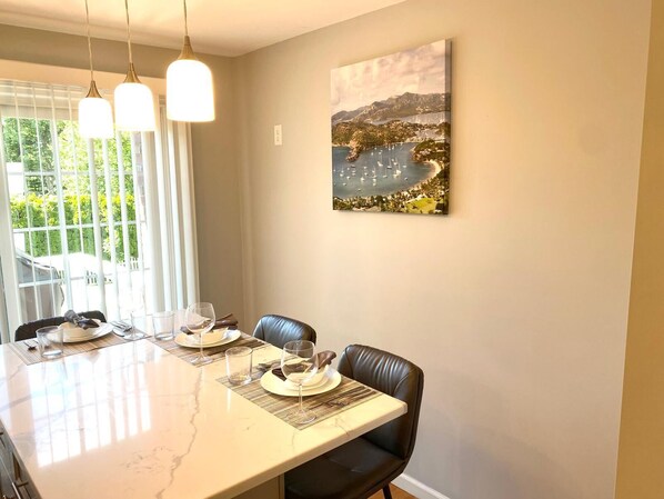 Un espace repas avec une table en marbre, des chaises en cuir noir et des luminaires suspendus.