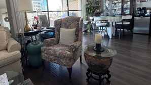 A living room with a sofa, armchair, and a glass coffee table. - Effortless Downtown Calgary Executive Condo | 6 to 8 Month Occupancy | $1,980/mo (Calgary)