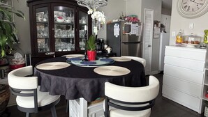 A dining area with a round table, white chairs, a dark tablecloth, and a glass cabinet with dishes. - Effortless Downtown Calgary Executive Condo | 6 to 8 Month Occupancy | $1,980/mo (Calgary)