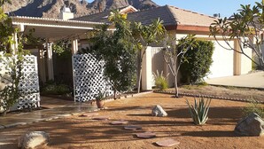Área residencial com uma casa, varanda coberta e um jardim ajardinado com pedras e plantas.