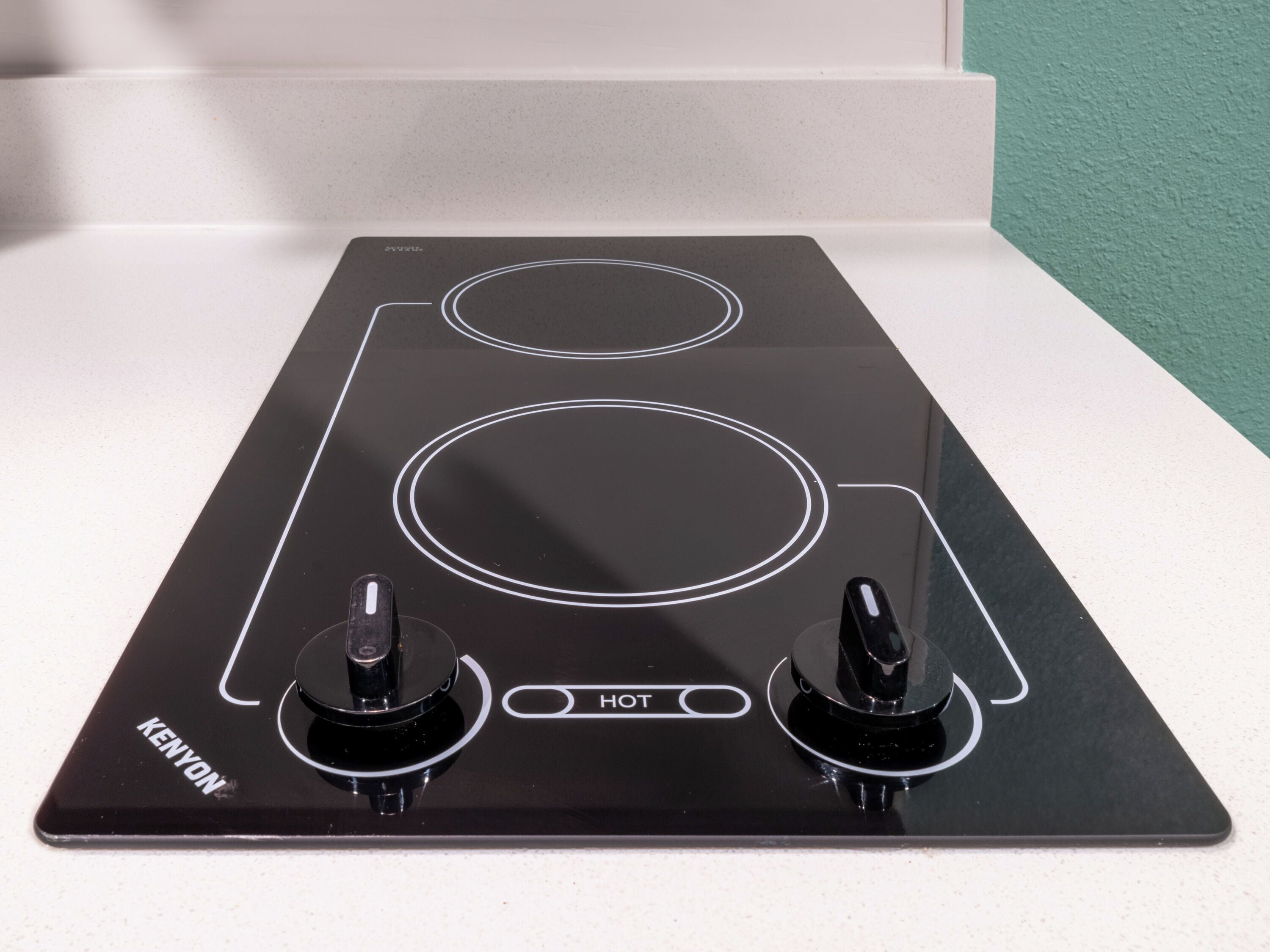 Una cocina eléctrica negra con dos hornillas y un panel de control que dice "HOT".
