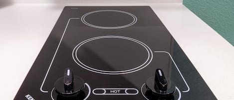 Una cocina eléctrica negra con dos hornillas y un panel de control que dice "HOT".