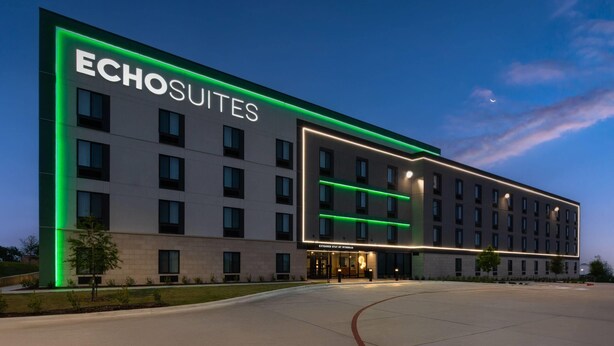 Et hotel med en moderne facade, store vinduer og et tydeligt 'Echosuites' skilt.