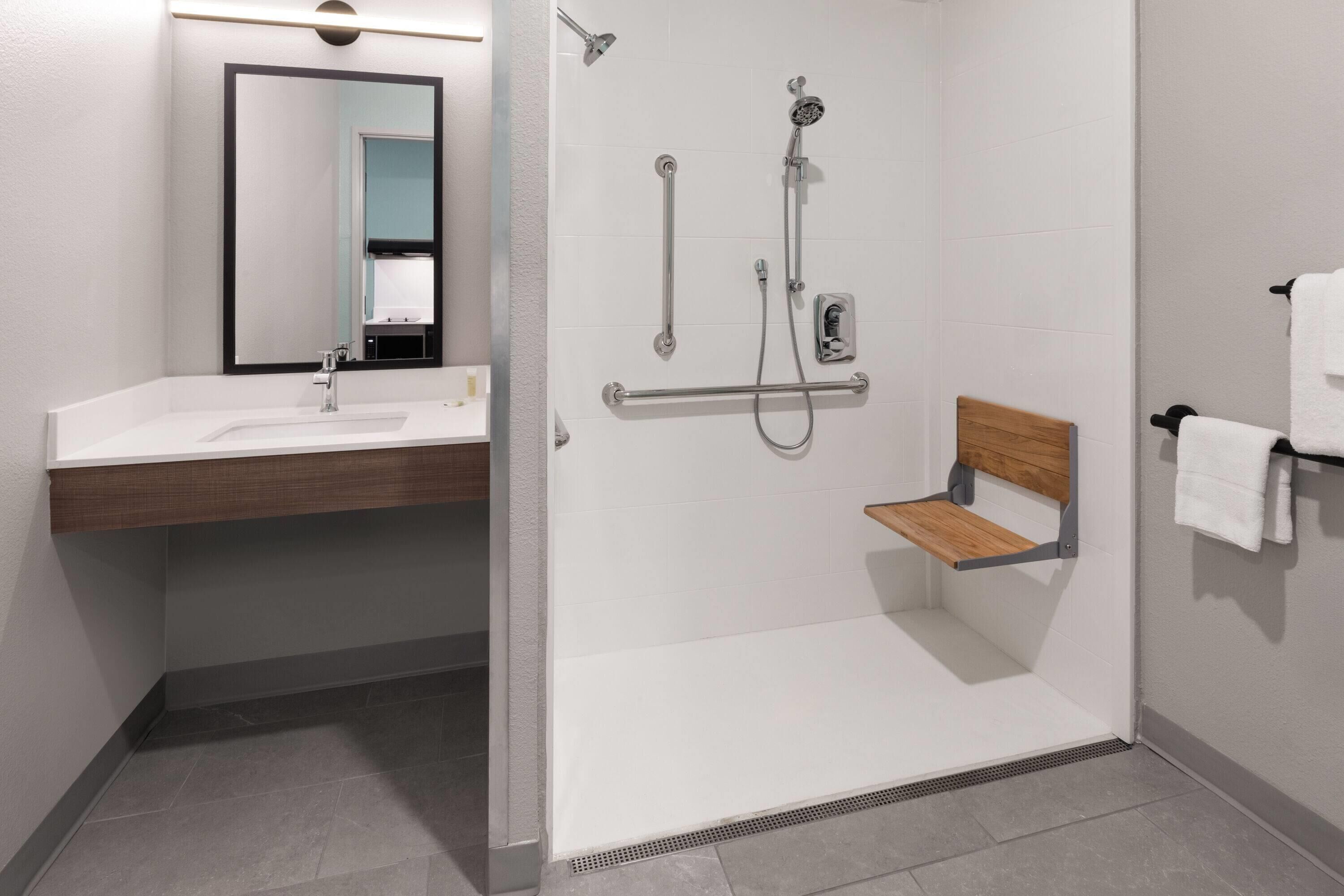 A modern bathroom with a shower, a sink, a mirror, and a towel rack.