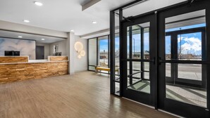A reception area with a wooden reception desk, a bench, and a large glass door leading outside.