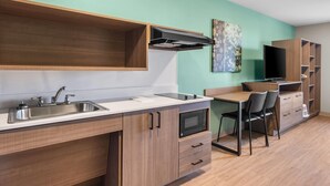 A modern kitchen with a sink, microwave, and wooden cabinets.