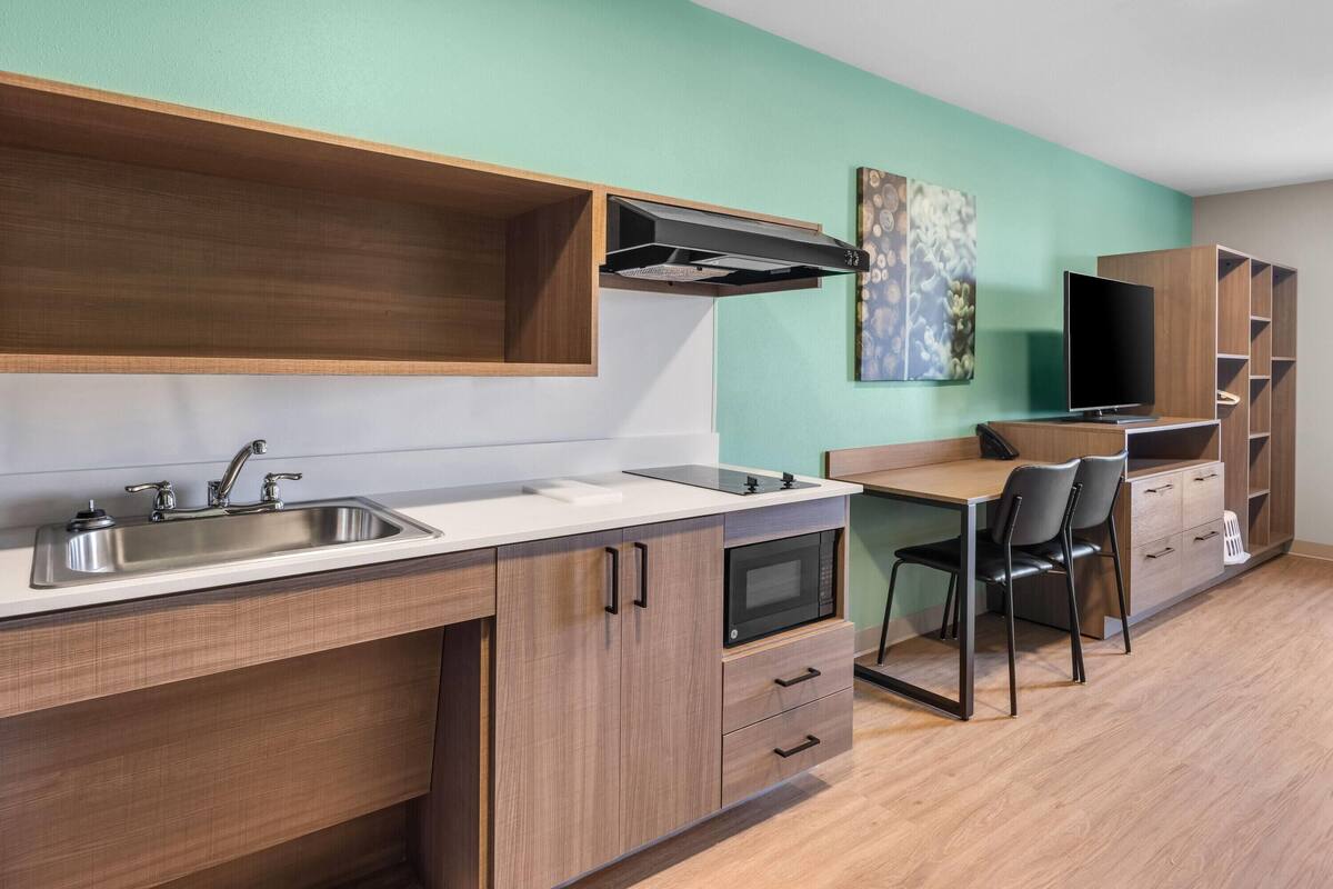 A modern kitchen with a sink, microwave, and wooden cabinets.