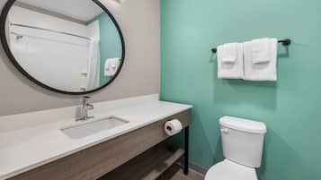 Une salle de bain avec un miroir rond, un lavabo, des toilettes et un porte-serviettes.