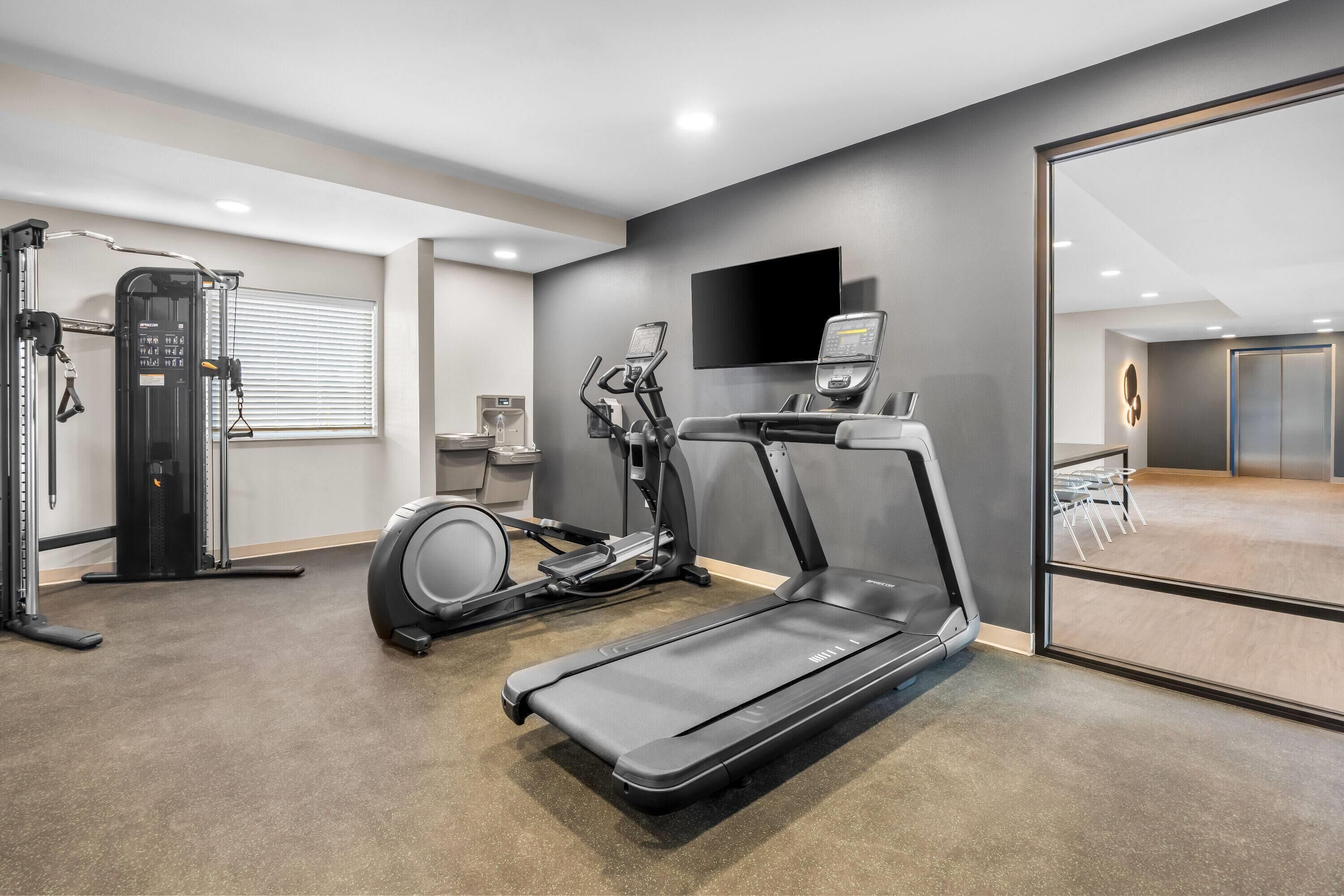 Een moderne sportschool met een loopband, elliptische trainer en krachttrainingapparaat.