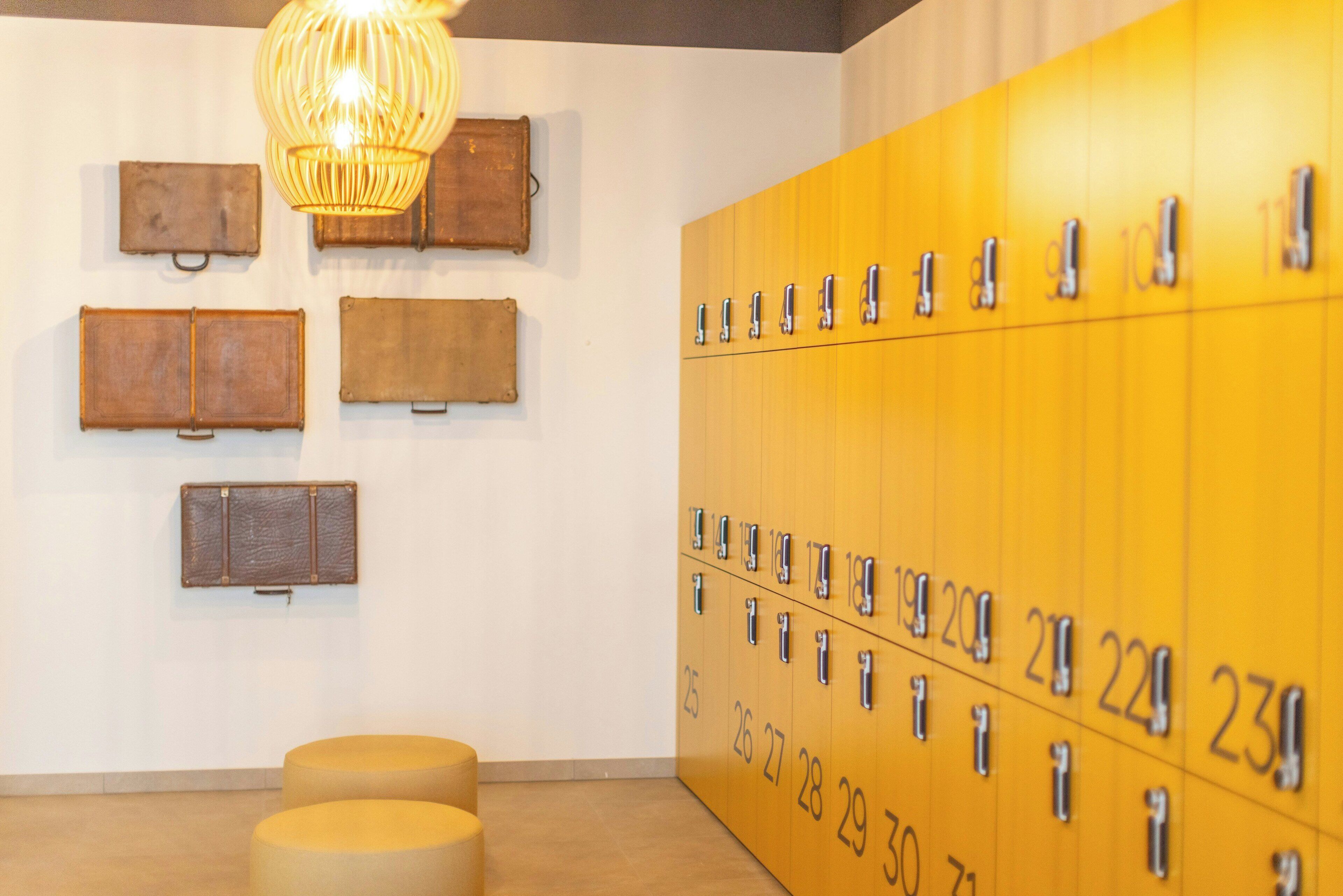 A locker room with numbered lockers, a hanging light fixture, and wall-mounted storage units.