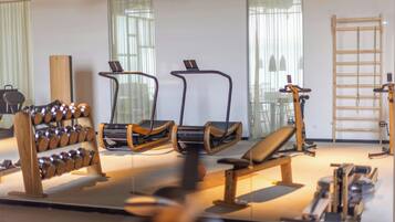 Un gimnasio con equipo de ejercicio, un estante de madera y una escalera.