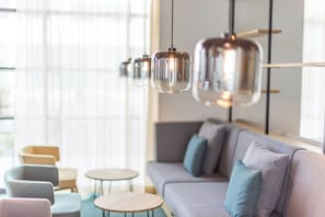 Interior moderno com sofá, cadeiras e luminárias pendentes.
