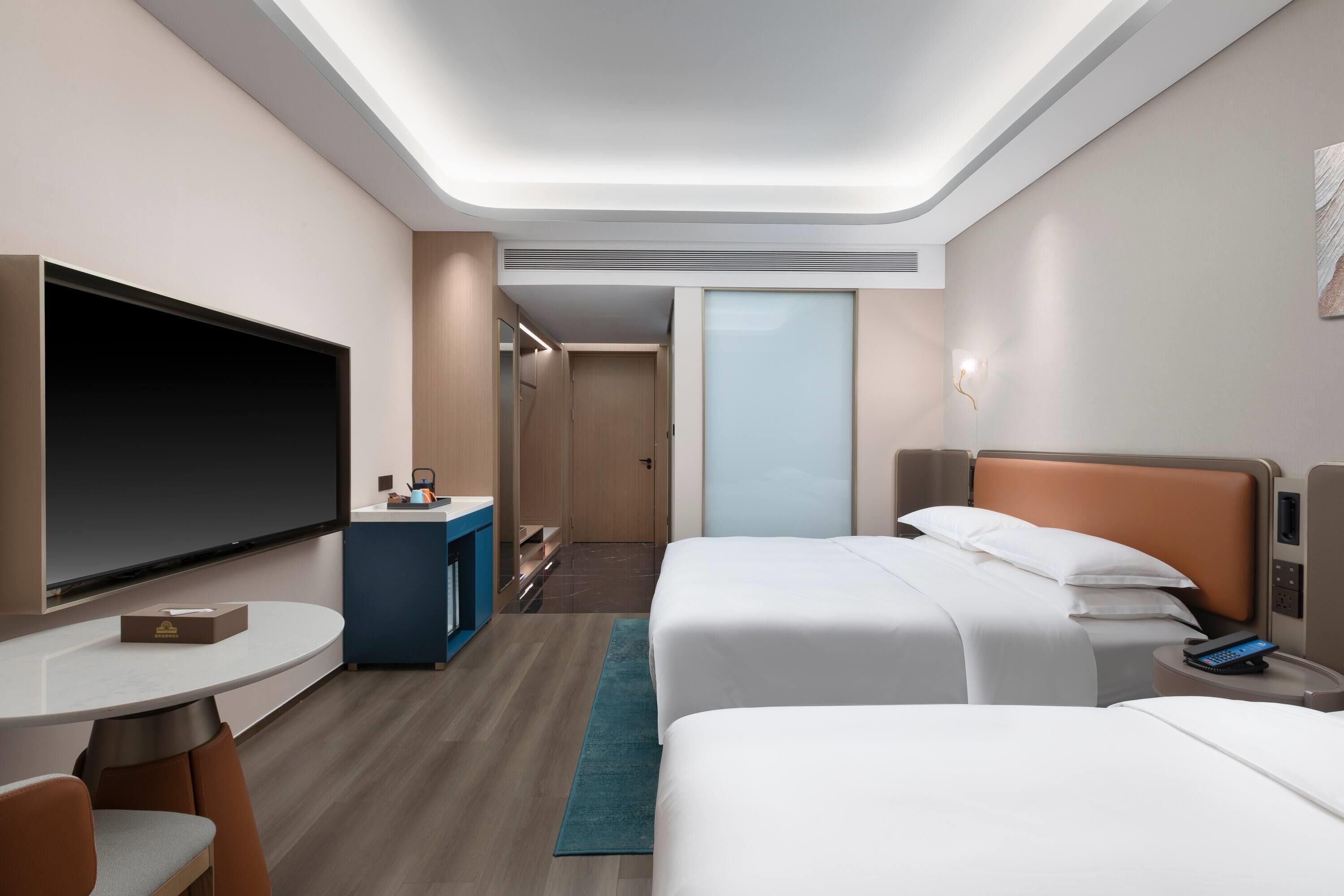 Une chambre d’hôtel avec deux lits, une télévision, un bureau et un mini-bar.