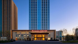 Un hotel con un cartel llamativo que dice "RAMADA" y "BY WYNDHAM" en la entrada.