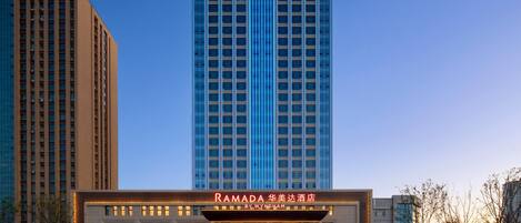 A hotel with a prominent sign reading "RAMADA" and "BY WYNDHAM" at the entrance.