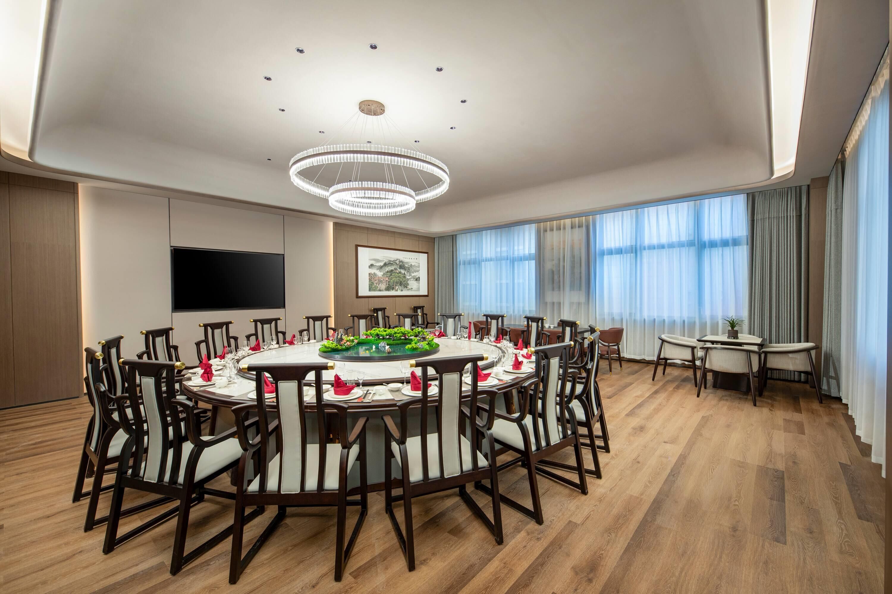 A spacious dining area with a round table set for a meal, surrounded by chairs.