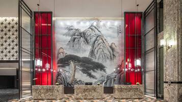 Un vestíbulo con una pintura tradicional china de paisaje, detalles en rojo y un diseño moderno.