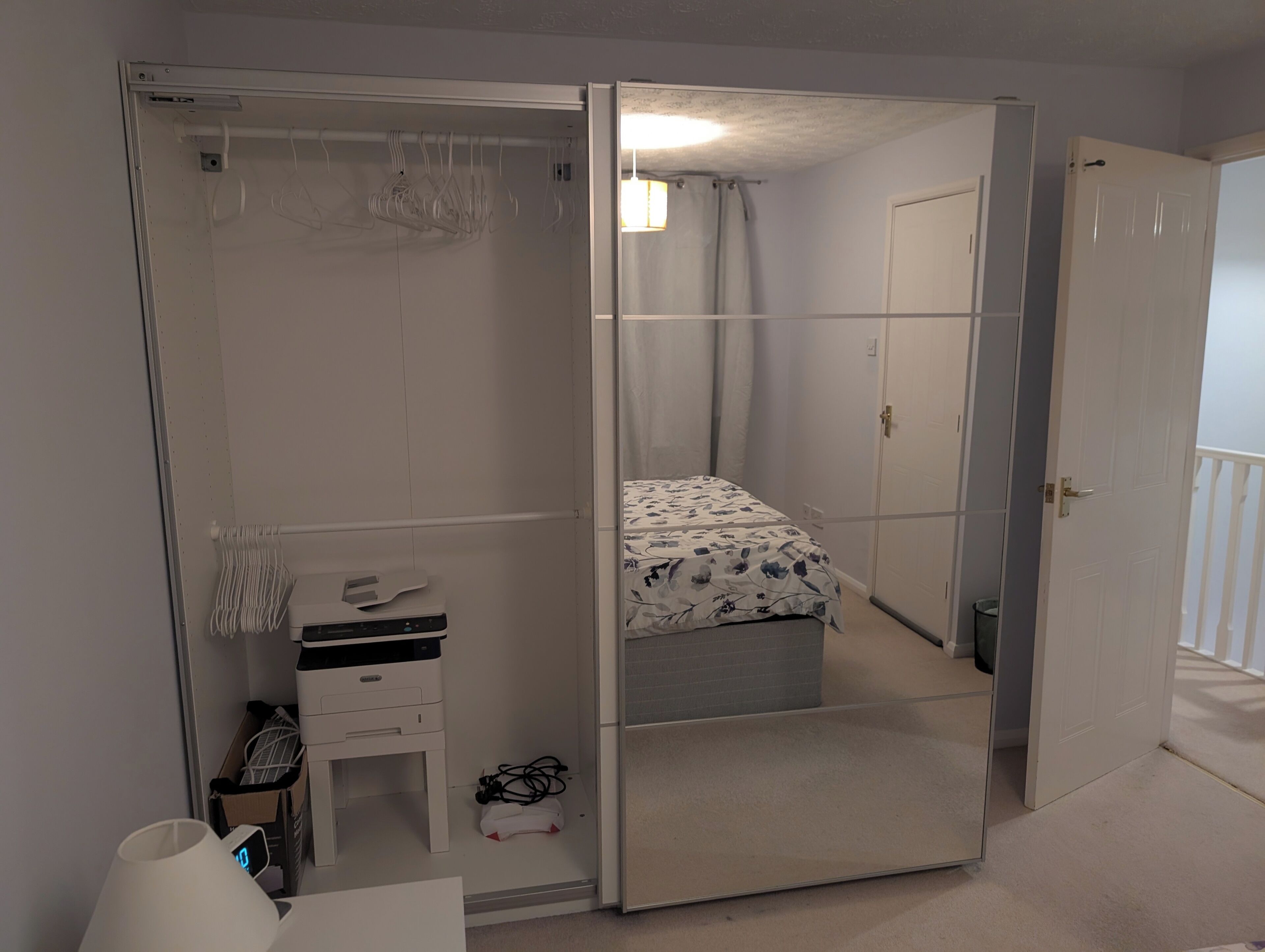 A bedroom with a bed, a desk, a chair, a wardrobe, and a mirror.