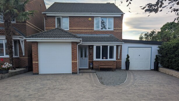 A two-story house with a garage, a covered porch, and a driveway. - Spacious 3 bedroom Family house with games room in quiet area (Braunstone Town)