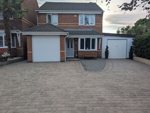 Una casa a due piani con garage, un portico coperto e un vialetto.