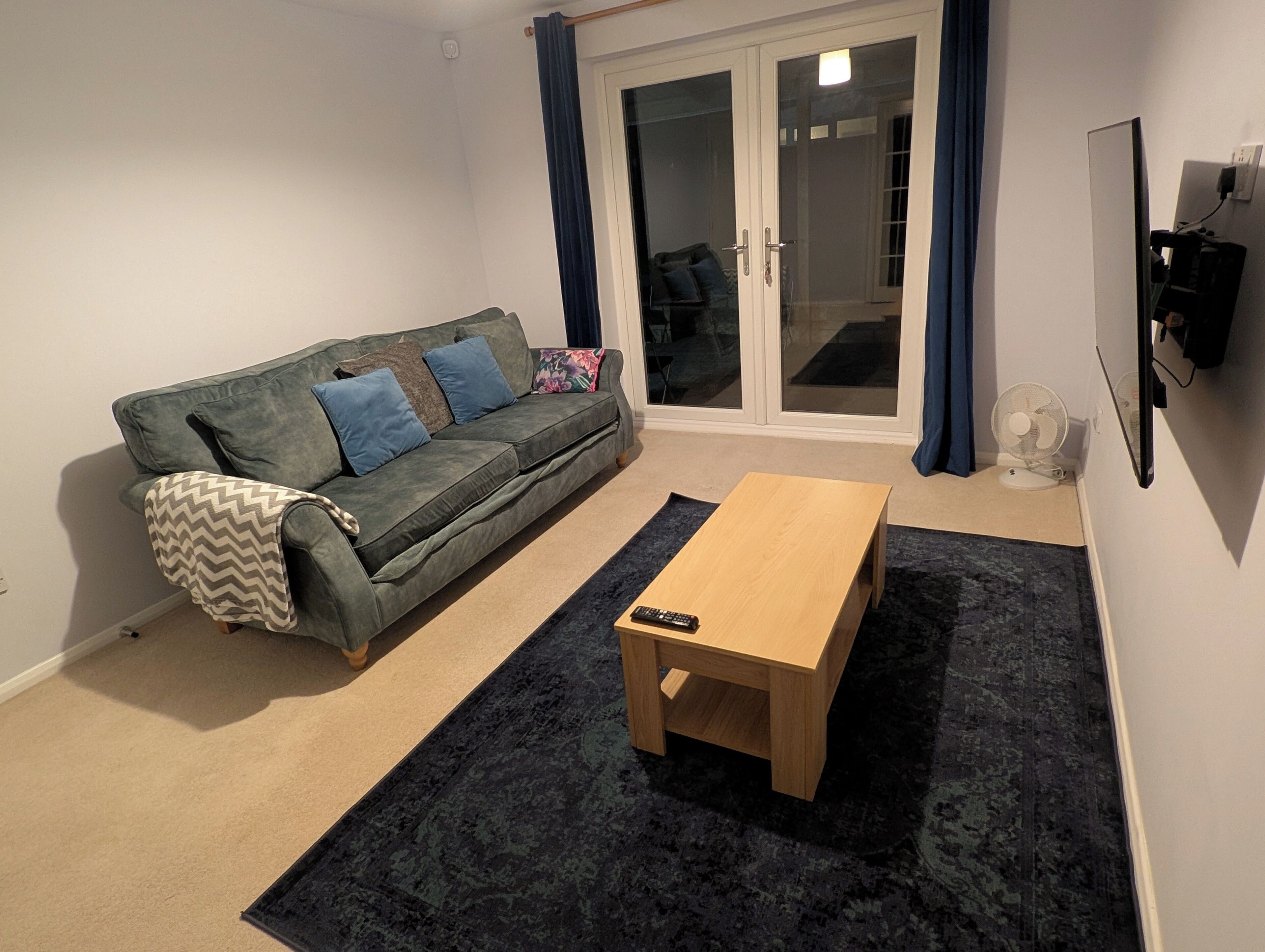 A living room with a sofa, a coffee table, and a sliding glass door leading to a balcony.
