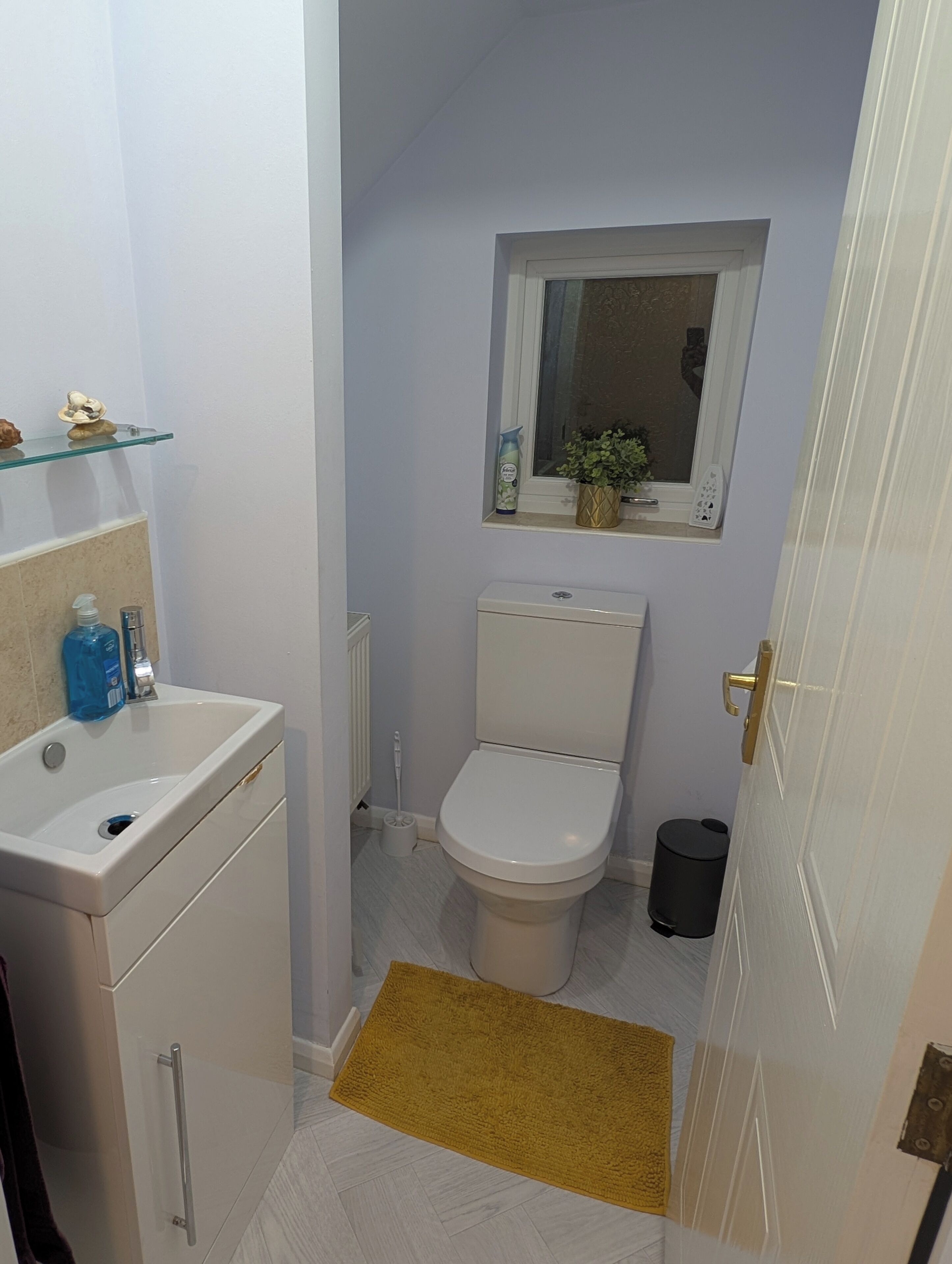 A compact bathroom with a toilet, a sink, a small window, and a radiator.