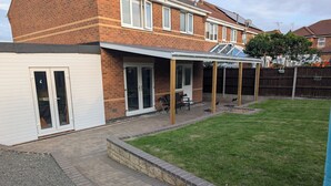 A residential backyard with a patio, a lawn, and a brick pathway. - Spacious 3 bedroom Family house with games room in quiet area (Braunstone Town)