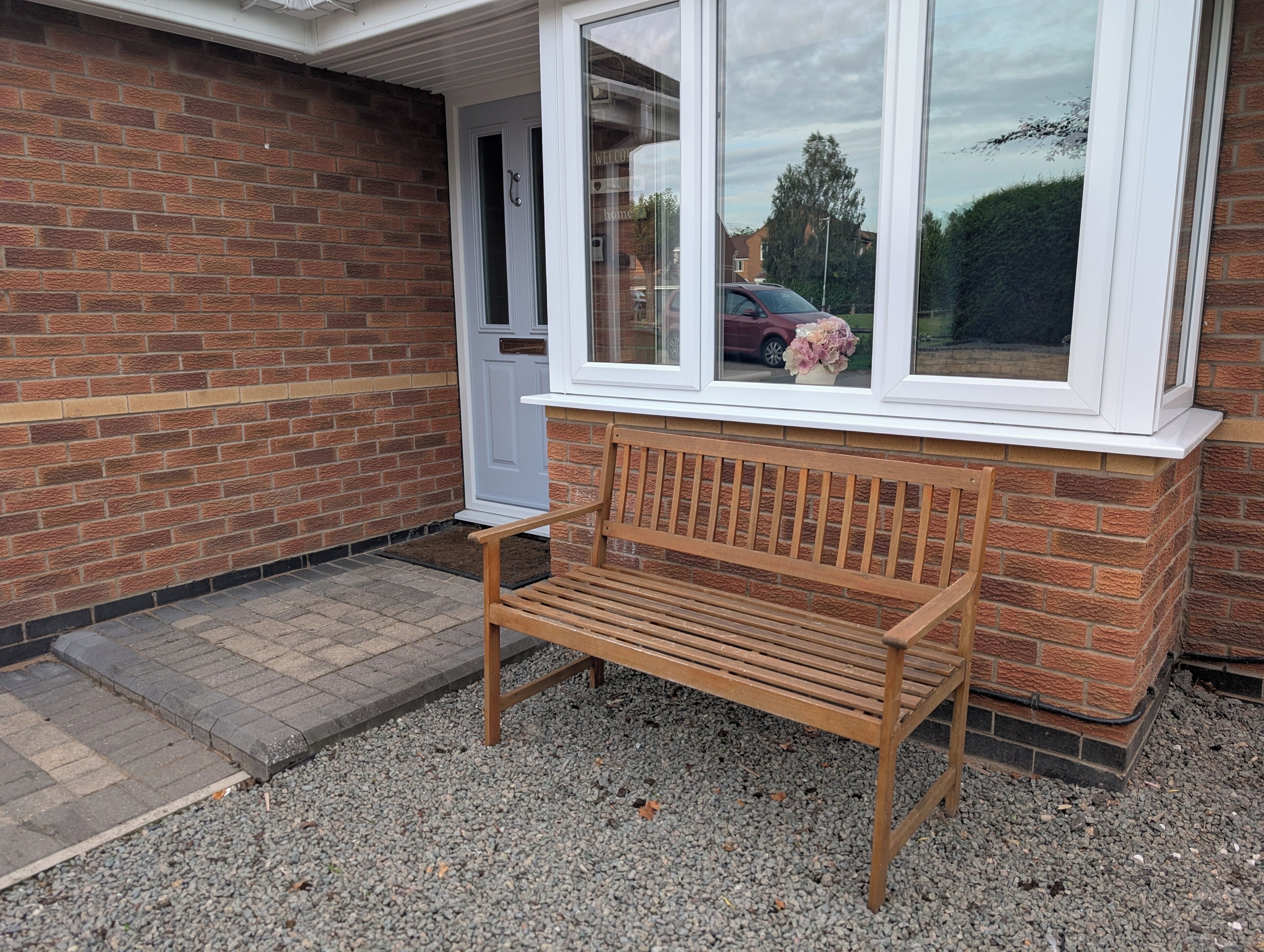 Un banc en bois se trouve devant une maison dont la porte et les fenêtres sont peintes en blanc.