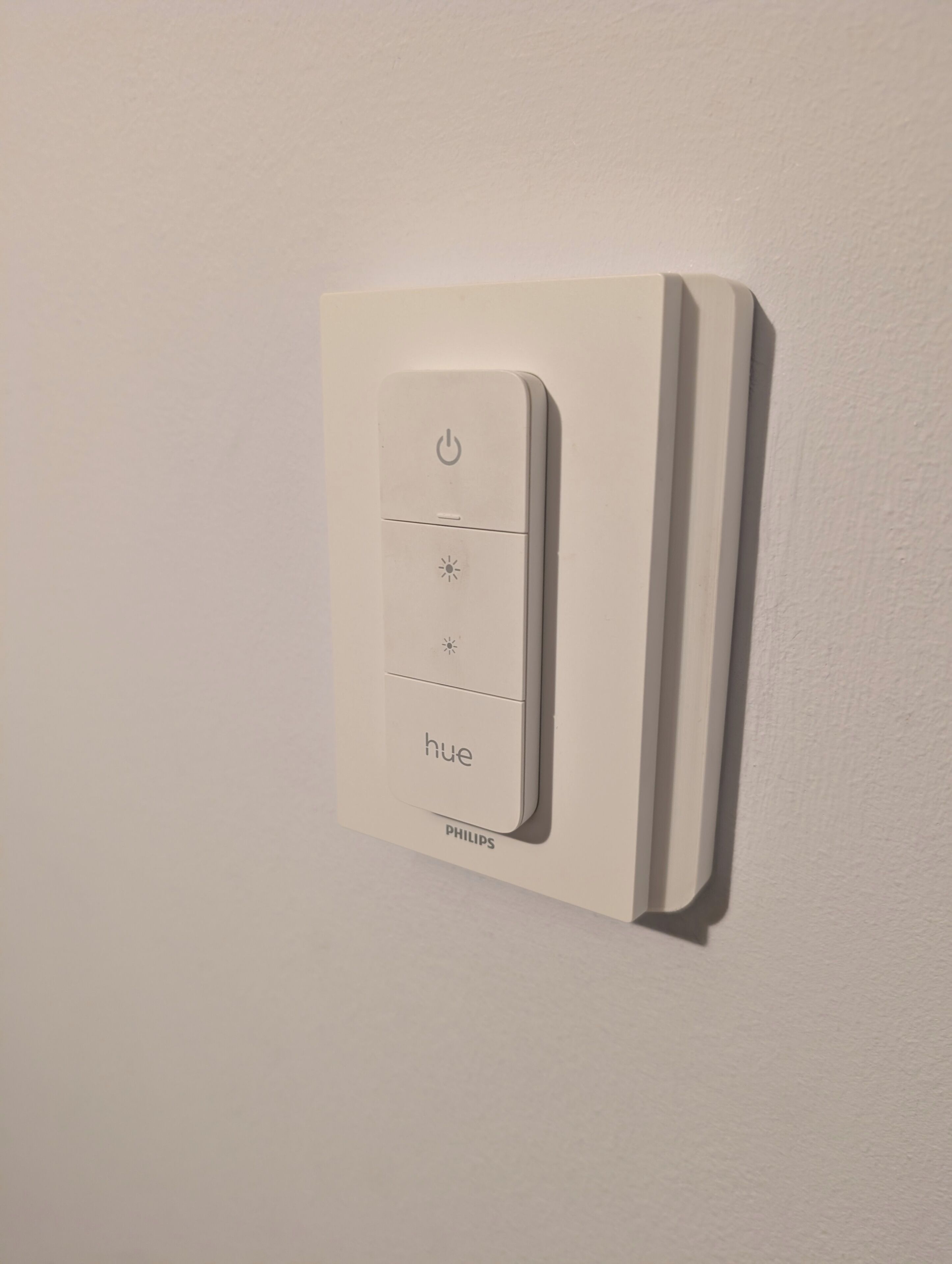 A Philips Hue light switch on a white wall.