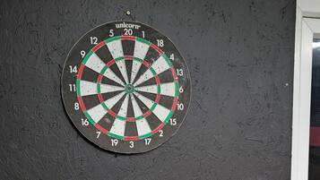 Eine Dartscheibe an einer Wand mit strukturierter Oberfläche und einem geometrischen Muster darunter.