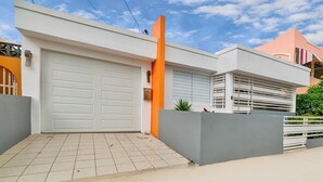 Une maison moderne avec un garage, une haute colonne orange et une clôture grise.