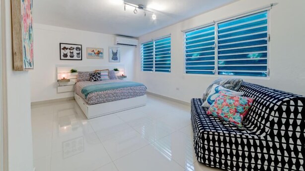 Une chambre à coucher moderne avec un lit, un canapé et une fenêtre équipée de stores.