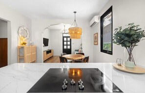 A modern kitchen with a black countertop, a round dining table, and a hanging light fixture. - Casa Santurce: Boho-chic home with Rooftop Oasis (Rosario)