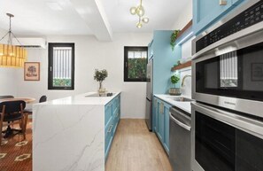 Una cocina moderna con una isla de mármol, electrodomésticos de acero inoxidable y armarios azules.