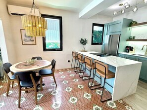 Une cuisine moderne dotée d’un îlot central, de tabourets de bar et d’une table à manger avec des chaises.