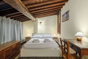 Une chambre à coucher avec un lit en bois, deux tables de chevet avec des lampes, un bureau en bois et un tableau accroché au mur.