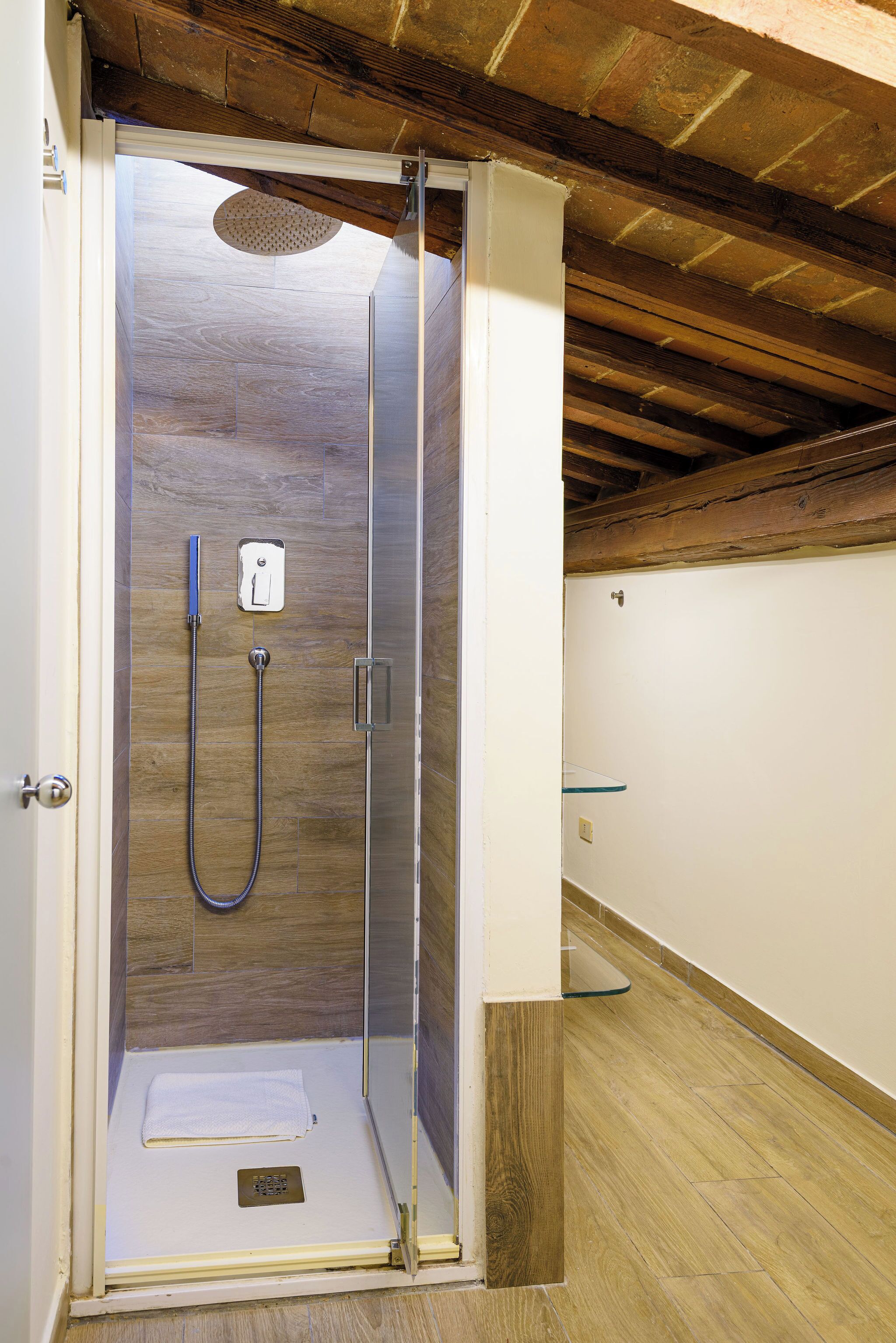 A walk-in shower with a wooden ceiling and tiled walls.