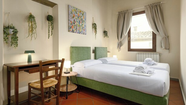 A bedroom with two beds, a desk, a chair, and hanging plants. - Florence Slow-Life Flat in Oltrarno (Firenze)
