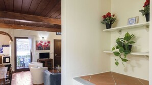 A living room with a wooden ceiling, a dining area with a table and chairs, and a kitchen visible through an archway. - Florence Slow-Life Flat in Oltrarno (Firenze)