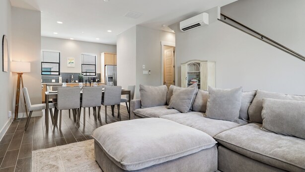 A modern living room with a sectional sofa, a dining area with chairs, and a kitchen in the background. - 3BR Downtown SA Home w/ Garage, Walk to Alamodome (San Antonio)